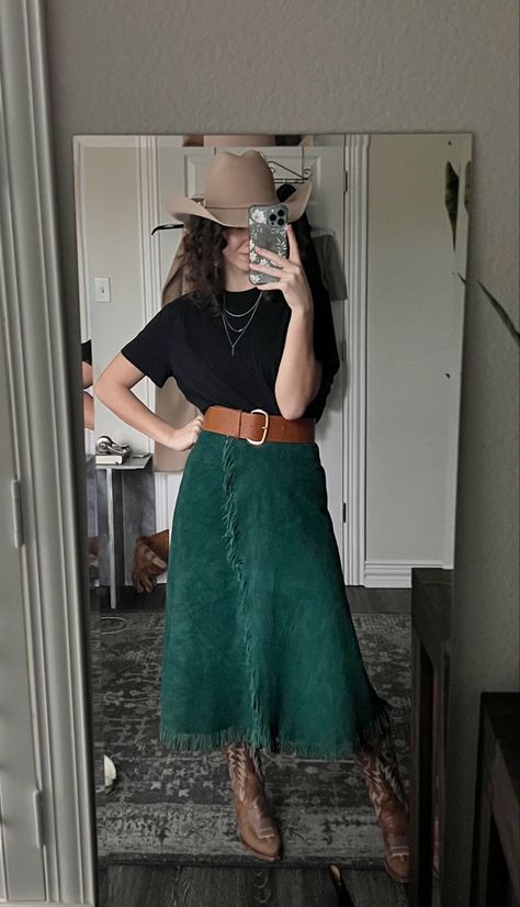 Green courdoroy fringe skirt paired with a basic black tee and brown cowgirl boots and hat. Additional accessories includr a layered necklace and wide brown belt. Long Skirt And Cowgirl Boots Outfit, Country Boots Dress Outfit, Skirt With Western Boots, Edgy Western Outfits Women, Cute Outfits Cowgirl, Cowgirl Boots Skirt Outfit, Cowgirl Boots With Skirt, Long Western Skirts Outfit, Cowgirl Skirts