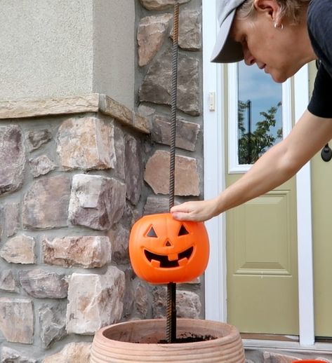 What says fall more than pumpkins? Here is a super easy and inexpensive way to dress up your porch for fall.    Step 1: Get pumpkins  Run, do not walk, to Walmart where plastic pumpkin pails are only $1.00 while supplies last. For one planter, purchase 5 pumpkins.    Step 2: Rebar  Purchase 4' rebar rods and place them into a pot (yellow circles). Secure with stones and soil. I made two planters so I purchased 2 rebar rods and 10 pumpkins.    Step 3: Cut the Handles  We don't need the… Outdoor Fall Pumpkin Decor, Fall Porch Pots With Pumpkins, Pumpkin Outside Decor, Pumpkin In Flower Pot, Fence Post Pumpkins Diy, Pumpkin Porch Decorations Diy, Halloween Porch Diy Decorations, Stacked Pumpkins In Planter, Plastic Pumpkin Stack Front Porches