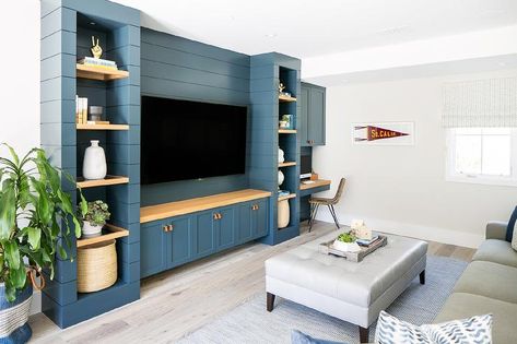 A flat panel television is mounted to a blue shiplap wall between wood floating shelves and over a wood countertop accenting blue shaker cabinets adorned with leather tab pulls. Blue Shaker Cabinets, Tv Built In, Built In Entertainment Center, Living Room Built Ins, Coastal Contemporary, Rack Tv, Transitional Living, Tv Wall Unit, Transitional Living Rooms