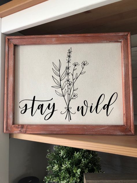 "Framed Spring Home Decor with the saying \"Stay Wild\" and featuring wildflowers. This Sign is made of vinyl on a canvas with a wooden frame and no glass. I have included twine attached to the back of the frame making it easy to hang. The sign also sits on a shelf, making it easy to add to your home decor. The wooden frame can be stained whatever color you choose to match your design style. In the example, the frame is stained Early American and then dry brushed to add a rustic farmhouse feel. Wildflower Sign, Wildflower Decor, Easter Sign, Spring Wildflowers, Decor Flowers, Easter Signs, Farmhouse Country, Spring Sign, Stay Wild