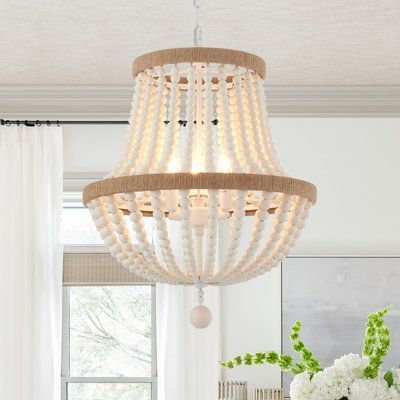 Crafted from metal(white-finished) and wood beads, this fixture features two tiers of rings in the hemp ropes decor for a traditional touch. Strands of oak white wood beads create a cage and hang below for a splash of glamour. This 3-light statement chandelier brings a glam feel and ambient light to your space. This fixture is height-adjustable, sloped-ceiling adaptable, and dimmer-switch compatible. It accommodates 60W bulbs (sold separately) and complements design styles from bohemian to moder Chandelier Wood, Boho Chandelier, Chandelier Farmhouse, Wood Bead Chandelier, Wood Light Fixture, Gold Ceiling Light, Bedroom Pendant, Rope Decor, Pendant Lighting Bedroom