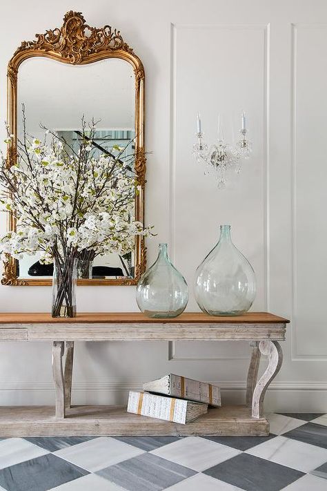 French foyer showcasing a gray wooden French console table with a gilt mirror and lovely recycled glass jugs atop white and gray harlequin floor tiles. French Foyer, French Console Table, Wood Floor Finishes, Foyer Flooring, White Leather Dining Chairs, Grey Wood Floors, Herringbone Wood Floor, Console Table Styling, Wood Armoire