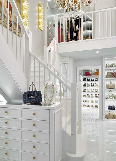 Glamorous 2 story custom closet boasts a tall white jewelry dresser accented with gold knobs and a glass top and placed against an all white staircase. Two Story Closet, 2 Story Closet, Transitional Closet, Master Closets, House Of Pain, Luxury Closets, Closets Design, Dressing Room Closet, Walking Closet