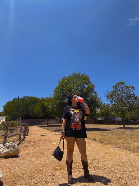 A girl in brown cowboy boots, a black Naruto ichiraku ramen shop tshirt drinking Starbucks and holding a black purse. The background is a cloudless sky with some trees in the foreground and a fence off to the side Tshirt And Cowboy Boots, Cowboy Boots Vintage, Cowboys Boots, Oversize Tshirt, Boots Vintage, Oversized T Shirt, Aesthetic Fashion, Oversized Tshirt, Cowboy Boots