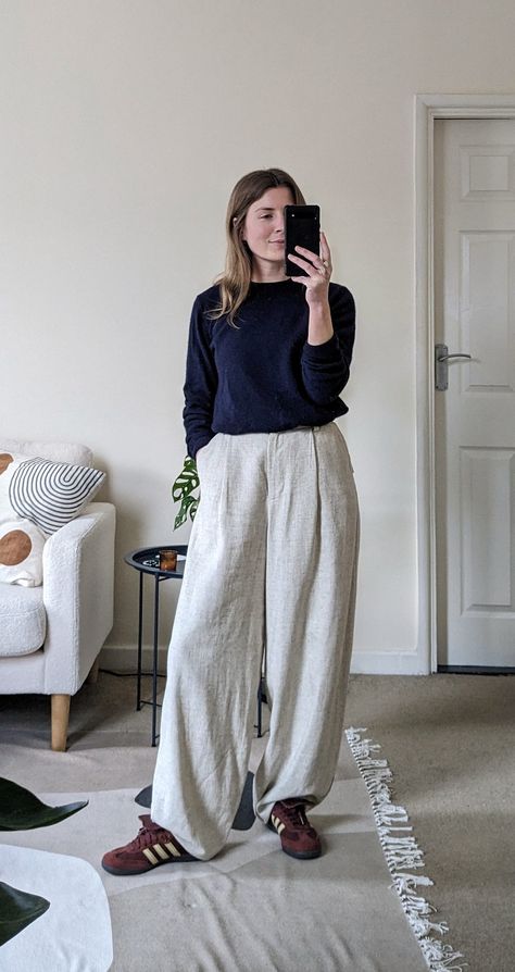 A woman stands in a living room. She wears a navy cashmere sweater, cream linen trousers and burgundy coloured adidas sneakers. Cream Linen Trousers Outfit, Navy Linen Trousers Outfit, Navy And Cream Outfit, Navy Sweater Outfit, Navy Linen Trousers, Linen Trousers Outfit, Elevated Casual Outfit, Navy Cashmere Sweater, Outfit Navy