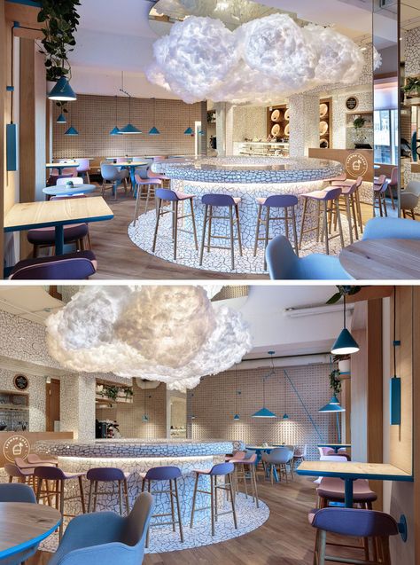 A large cloud light hangs in the middle of this modern cafe above a circular bar area, that features a white chipped tile surface. #Cafe #CafeDesign #InteriorDesign #CloudLight Clouds Interior Design, Cloud Cafe Design, Cloud Interior Design, Circular Bar, Restaurant Design Inspiration, Cloud Light, Cafe Concept, Themed Cafes, Art Cafe