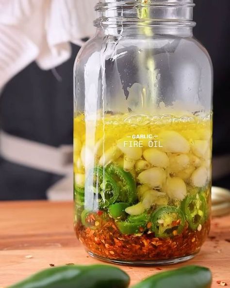 @healthfoodrevival on Instagram: "Garlic Fire Oil. By @ryanmichaelcarter  This is a spicy infused olive oil with fresh garlic, jalapeños, and crushed red pepper. It’s great on pasta, bread, pizza— you name it. Use it the same as you would for olive oil.  + STORAGE Once filtered, the Garlic Fire Oil will last about one month. No refrigeration is needed.  DIRECTIONS  + STEP 1: HEAT Submerge a 1-qt mason jar in a pot full of water and bring to a boil. Meanwhile, heat the olive oil to 350°F.  + STEP 2: COMBINE Carefully remove the mason jar from the water with tongs (WARNING! The jar and water will be extremely hot and will burn if touched). Ensure no water is left in the jar, then add the red pepper, jalapenos, and garlic. We leave the garlic cloves whole for a lighter garlic flavor. However, How To Infuse Olive Oil With Garlic, Garlic Fire Oil, How To Make Olive Oil At Home, Garlic Infused Olive Oil Recipes, Olive Oil Infused Recipes, Diy Flavored Olive Oil, Infused Olive Oil Recipes, Marinade Sauces, Oil Infusion