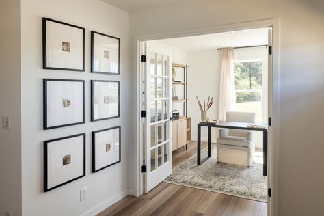 A wall with six framed art pieces leads to open French doors that reveal an office with a cream chair and black desk. Flex Space Ideas, Home Office Playroom, Flex Room Ideas, Flex Space, Clayton Homes, Comfy Seating, Flex Room, Animal Room, Hobby Room