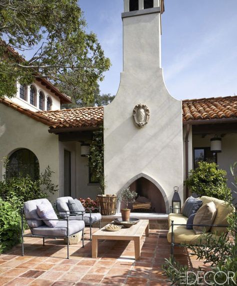 The courtyard's painted-bronze furniture is by Niermann Weeks; the chair cushions are covered in a Rose Tarlow Melrose House fabric and the sofa cushions are in a Duralee fabric; the teak cocktail table is by Holly Hunt, the flooring is of reclaimed terra-cotta tiles, and the fireplace's 17th- century armorial cartouche was found at Bonhams. Spanish Courtyard, Desert House, Mediterranean Style Homes, Patio Fireplace, Mediterranean Home Decor, Spanish Style Home, California Desert, Casas Coloniales, Spanish Style Homes