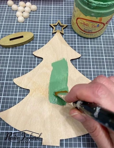 Make your own Wood Christmas Tree Décor with this simple holiday crafting idea! Paint A Christmas Tree On Wood, Unfinished Wood Christmas Tree, Painted Wood Trees Christmas Decorations, How To Paint Unfinished Wood Crafts, Simple Wooden Christmas Tree, Decoupage Wooden Christmas Trees, Painting Wood Christmas Trees, Painting A Christmas Tree On Wood, Dollar Tree Wood Christmas Crafts