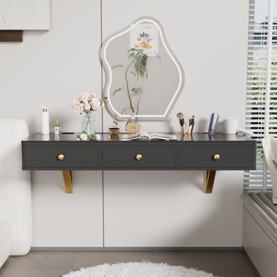 This contemporary makeup vanity elevates the experience of daily rituals. Its floating design is a space-saving marvel, featuring a sleek MDF and glass top supported by elegant gold metal brackets. With its built-in electronic equipment holder and various-sized pails, it's ingeniously designed to organize blow dryers and makeup tools, making it an ideal choice for both makeup and hairdressing needs. The wall-mount setup allows for customized height, ensuring ergonomic comfort. This piece doesn't Hanging Makeup Vanity, Beauty Area In Bedroom, Small Bathroom Makeup Vanity, Small Makeup Vanity Ideas, Small Space Vanity Ideas, Small Makeup Area, Built In Makeup Vanity In Bathroom, Floating Vanity Makeup, Makeup Station In Bedroom