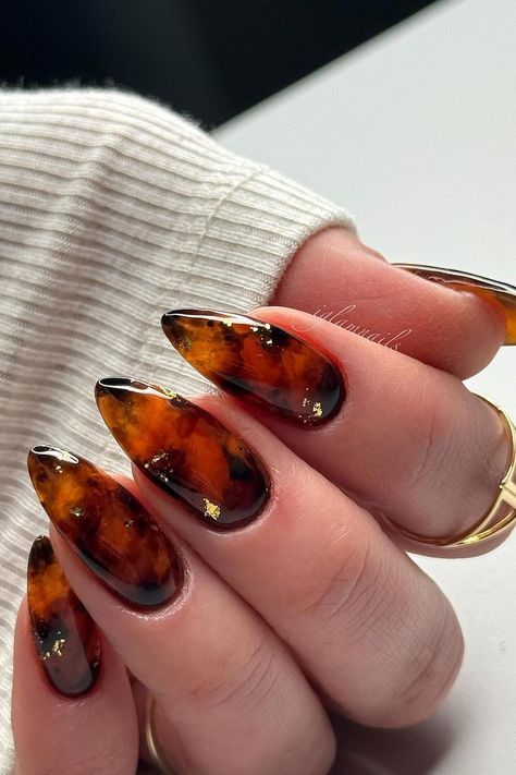 These almond-shaped nails feature a stunning tortoise shell design. Rich amber and brown tones blend seamlessly, creating a warm, organic pattern. Subtle gold flakes are carefully placed throughout, adding a touch of luxury to the sophisticated look. Each nail is beautifully glossy, amplifying the intricate details of the design. Perfect for a chic and polished style!  // Photo Credit: Instagram @iglamnails Trending Nail Art Designs, Tortoise Shell Nails, Shell Nails, Sophisticated Manicure, Trending Nail Art, Retro Nails, Fall Nail Trends, Pink Ombre Nails, Trending Nails