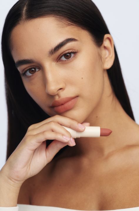 Model holding lipstick with glowing skin Poses With Lipstick, Lipstick Shoot Ideas, Model Holding Product, Lipgloss Model Photoshoot, Applying Lipstick Photography, Holding Lipstick, Lipstick Photoshoot Ideas Product, Lipstick Photography Model, Lipstick Model