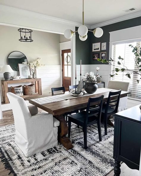 Shiplap half wall in entryway provides background for a wood console and black framed mirror. Shiplap wall continues into emerald green dining room with a modern chandelier over wood dining table. Varying black and white chairs sit around the table. Dining Room Entryway Combo, Shiplap Entryway, Green Dining Room, Dark Green Walls, Front Door Entryway, White Shiplap Wall, Dining Ideas, Faux Brick Walls, Room Makeovers