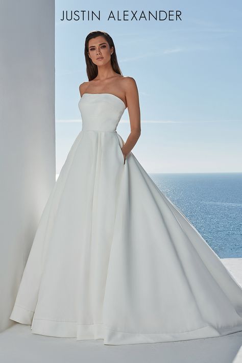 This satin ball gown is elevated and uncomplicated. Designed with a straight neckline accented with horizontal seaming that compliments the box pleats in the skirt. Detailed with pockets, a satin hem, and buttons to the end of the train. Plus Size Ball Gown, Justin Alexander Bridal, Justin Alexander Wedding Dress, Satin Ball Gown, Lillian West, Bridal Elegance, Justin Alexander, Wedding Dress Pictures, Satin Wedding