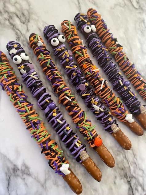 12 Halloween pretzel sticks covered in milk chocolate and Halloween sprinkles.  *note sprinkles will vary depending on availability. All sprinkles used are halloween theme.  **Important chocolate is particularly heat sensitive. High temperatures can cause the chocolate to melt and affect the decorative elements we've carefully prepare. Chocolate Covered Pretzels Aesthetic, Halloween Pretzel Rod Ideas, Halloween Themed Pretzel Rods, Chocolate Dipped Pretzels Halloween, Halloween Candy Apple Bar, Halloween Candy Homemade, Halloween Chocolate Pretzels, Halloween Candy Melt Ideas, Chocolate Dipped Halloween Treats