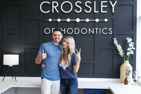 Crossley Orthodontic Office. Black accent wall in reception office. @JaneneCrossley Accent Wall Reception Area, Dental Office Accent Wall, Dental Office Wall Decor, Orthodontic Office Design Interiors, Accent Wall With Logo, Orthodontist Office Design, Orthodontics Office, Orthodontic Office Design, Orthodontist Office