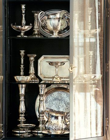 "A double-door cabinet from KNF Designs displays a sculptural collection of old silver and antiqued mercury glass candlesticks, all used for entertaining"  Tranquil Townhouse - Alabama - Susan Ferrier - House Beautiful Mercury Glass Candlesticks, Silver Display, Bronze Accessories, Silver Items, Silver Trays, Silver Decor, Mercury Glass, Absinthe Fountain, Silver Pieces