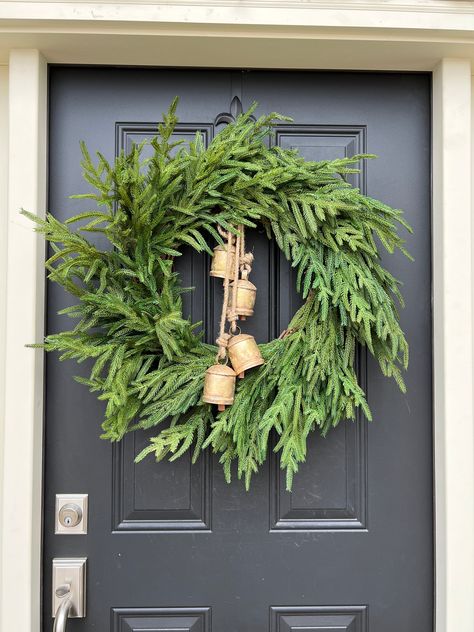 Deck your door with holiday cheer using our Norfolk Pine Wreath, an elegant nod to Christmas traditions. This vibrant green wreath is adorned with rustic bells that softly chime in the winter breeze, calling to mind sleigh rides and carolers at your doorstep. Perfect for those who love the sound of Christmas as much as the sights, this wreath will bring joy and a touch of nostalgia to every visitor. Suitable for both indoor and covered outdoor use. Wreath With Bells And Ribbon, Green Christmas Wreath Ideas, Norfolk Pine Wreath, Outdoor Wreaths On House, Christmas Wreath With Bells, Wreath With Bells, Holiday House Decor, Sleigh Rides, Norfolk Pine