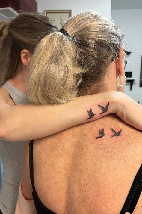 Matching mother-daughter tattoos featuring small birds in flight on the back and wrist, symbolizing freedom and connection. Mother Daughter Tattoos Hummingbird, Cute Mother And Daughter Tattoos, Mama Daughter Tattoos, Mother Daughter Bird Tattoos, Grandmother Mother Daughter Tattoos, Tattoo Mum And Daughter, Tattoos For Mother Daughter, Mom Matching Tattoos, Tattoos With Mom And Daughter