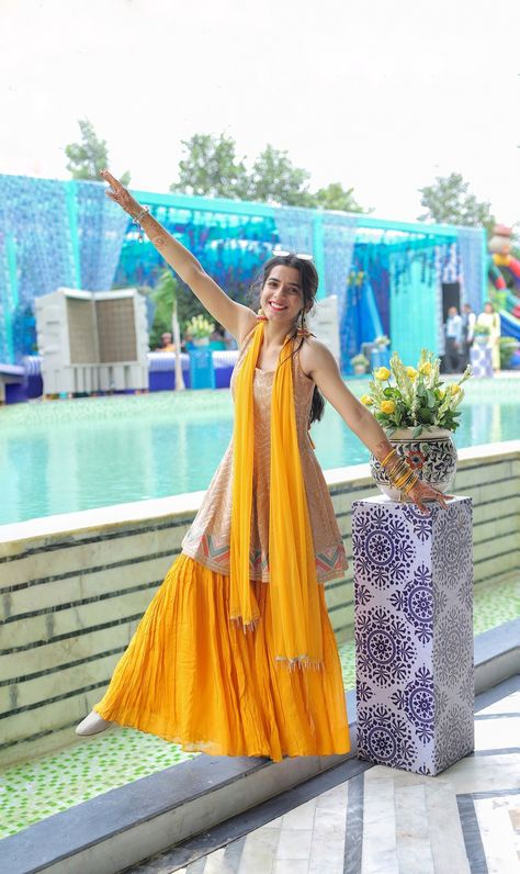 when it comes to haldi outfits for brides, there’s so much one can experiment with. you can pick your haldi ceremony outfit to be of flowy & easy-breezy silhouettes like a cape style co-ord set, a palazzo pants with a crop top or a light weight, tiered lehenga in a beautiful floral print. Haldi Theme Dress For Family, Haldi Ceremony Outfit For Sister Indian, Haldi Ceremony Outfit For Sister, Dress For Haldi, Dresses For Haldi Ceremony, Haldi Ceremony Outfit For Bride, Dress For Haldi Function, Haldi Function Dress, Plazo Dress