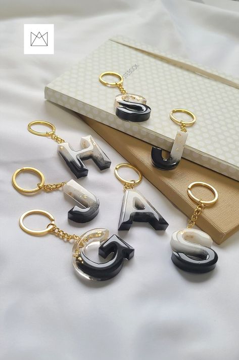 A couple of Black and White Resin Letter Keychain with Gold flakes, attached to gold metal keychain. Black And White Resin Keychain, Resin Keychain Photography Ideas, Keychain Photoshoot Ideas, Simple Resin Crafts, Resin Photography Ideas, Keychain Photography Ideas, Resin Photography, Giveaway Graphic, Resin Letter Keychain