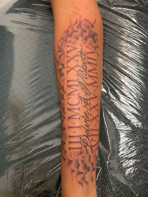 Celebrate Life: 20 Long Live Tattoo Ideas for Dark Skin Roman Numbers Tattoo Forearm, Roman Numerals Memorial Tattoo, Tattoo Designs Men Roman Numerals, Name With Roman Numeral Tattoo, Two Roman Numeral Tattoos, Roman Numeral Tattoo Men Arm Half Sleeves, Roman Numeral Memorial Tattoo, Roman Numeral Tattoo Men Forearm, Tattoo Ideas For Dark Skin