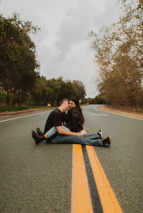 Couple sitting together in the street no one around, raining, green foliage all sides, he’s kissing her cheek they have arms and legs wrapped around each other. Pure love. Rainy Photoshoot, Rainy Day Photos, Couples Beach Photography, Couple Shoots, Road Photography, Couple Picture Poses, Engagement Photo Poses, Couple Photoshoot Poses, Couple Photography Poses