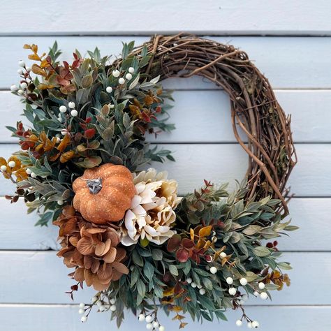 This beautiful fall pumpkin wreath will be the perfect addition to your front door this holiday season to greet your guests.  Arranged on a natural grapevine base this wreath has a orange pumpkin with a brown hydrangea and cream peony, surrounded with berries, ruscus greenery and eucalyptus with different shades of fall colors. All materials are high quality faux.  This wreath is made on a 14" grapevine base and measures approximately 18" from leaf tip and across in the widest area. Wreaths make perfect gifts for any occasion - for teachers, gift for mom, anniversaries, showers, birthdays, housewarming and even real estate.  Please be sure to keep wreath inside or covered outside. Keep out of direct sunlight and away from moisture.  Be sure to follow my shop for sales and new items. You ca Ruscus Greenery, Pumpkin Fall Wreath, Halloween Door Decor, Wreath Inside, Fall Wreath For Front Door, Door Wreaths Diy, Door Wreaths Fall, Fall Thanksgiving Decor, Halloween Door Decorations