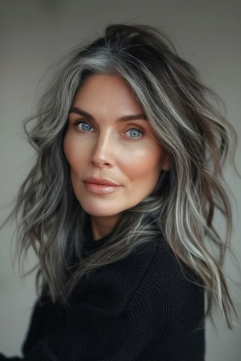 Woman with striking grey hair and blue eyes, gazing directly at the camera with a subtle smile, against a neutral background. Blending Gray Hair With Lowlights, Gray Hair Blending, Grey Brown Hair, Grey Blending, Hair Blending, Gray Balayage, Grey Hair Transformation, Black Cake, Grey Hair Inspiration