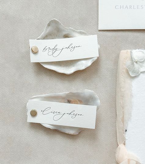 Personalization: Each oyster place card is meticulously crafted and customized with the names of your guests, adding a personal touch to your seating arrangement.Memories: Your guests will cherish these unique keepsakes as mementos of your special day, reminding them of the beauty and love shared at your classic beach wedding.BeachWedding #OysterPlaceCards #WeddingDecor #ModernElegance #ClassicBeachWedding Oysters Wedding Decor, Coastal Wedding Details, Beach Wedding Place Cards, Oyster Wedding Decor, Oyster Name Cards Wedding Ideas, Oyster Table Numbers, Oyster Place Setting, Coastal Wedding Place Settings, Oyster Place Cards