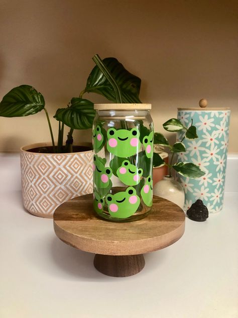 Enjoy your favorite beverage while falling in love with these adorable little frogs. 🐸 16oz capacity. Bamboo lids and glass straw add-ons are available. Jar Painting Ideas Cute, Jar Painting Ideas, Glass Jar Painting, Frog Cup, Banner Elk North Carolina, Smoothie Jar, Coffee Glass Cup, Painting Glass Jars, Trendy Water Bottles