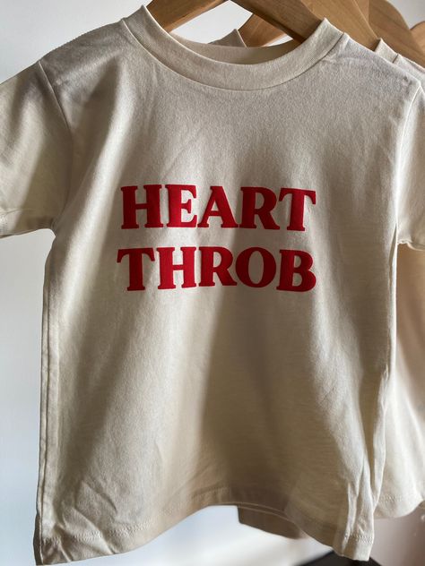 Heart Throb Tee Have the cutest littles ever made? This is the perfect tee for them! Not only great for Valentine's Day but can be worn year round! Bella Canvas unisex tee, natural color. 100% combed and wingspan cotton. Raised lettering. Offered in sizes 2T-5T Please allow 5-7 days max for production* Heart Throb, Valentines Tees, Heart Graphic Tee, Valentines Clothing, Kids Shirts Design, Cool Slogans, Silly Shirt, Slogan Tshirt, Toddler Humor