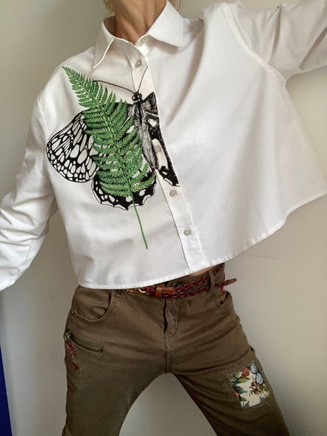 "Introducing our enchanting Hand painted  Fern plant and Butterfly wing art White Shirt, a captivating blend of nature-inspired artistry and contemporary fashion. This stunning white shirt is adorned with a beautifully hand-drawn graphic butterfly delicately positioned under fern leaf. Hand painted floral shirt would be amazing Birthday gift for daughter. Hand paint blouse also can be amazing mom birthday gift. Crafted with meticulous attention to detail, this shirt is a true testament to the fu Paint On Clothes, Butterfly Wing Art, Butterfly Wings Art, Painted Shirt, Wing Art, Paint Shirts, Wings Art, Diy Vetement, Fern Plant