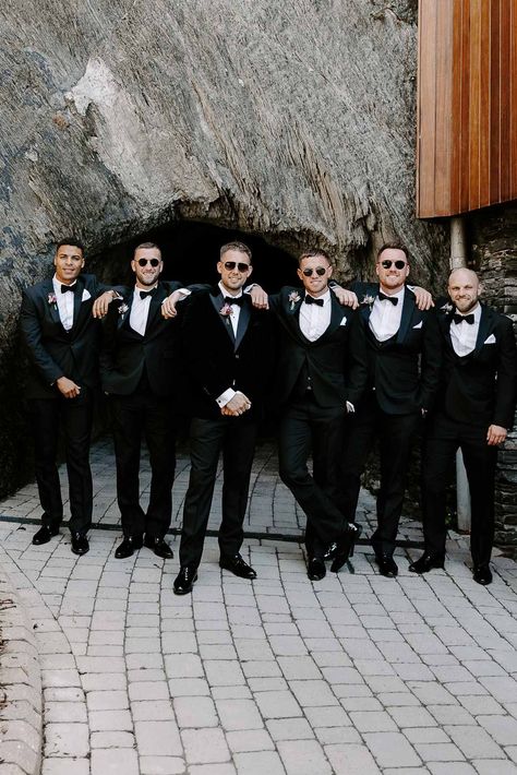 Grooms party wearing matching classic black-tie tuxedos, bow ties and grooms sunglasses | Becky Tranter Photography Groomsmen Sunglasses Photo, Groomsmen Outfits Black, Tuxedo For Groomsmen, Black Tie Groomsmen, Wedding Photoshoot Beach, Black Tie Beach Wedding, Black Tie Wedding Party, Groomsman Photos, Beaches Wedding