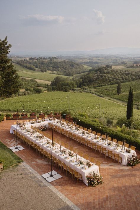 Long dining tables arrange for an outdoor wedding reception in Tuscany, Italy. Rolling hills captured in the backdrop. Long Tables For Wedding Reception, Long Outdoor Wedding Table, Wedding Themes Italy, Outdoor Wedding Long Tables, One Big Wedding Table, Tuscany Wedding Table Decor, Garden Wedding Italy, Italy Wedding Tuscany, Italian Vibes Wedding