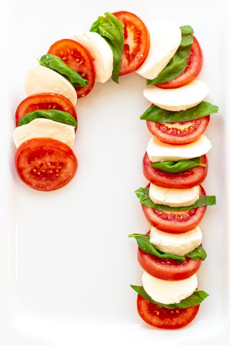 Festive Christmas Caprese Salad: Looking for a fun, easy-to-make salad this Christmas season? This Christmas Caprese Salad consists of tomatoes, bocconcini and fresh basil arranged in the shape of a candy cane. A delicious, simple salad that will add a fun, festive touch to your holiday table! | www.mapleandmango.com #christmas #salad #caprese #holidaysides Mozzarella Tomato Basil Candy Cane, Candy Cane Mozzarella Tomato, Christmas Caprese, Salad Caprese, Christmas Salad Recipes, Christmas Appetizers Easy, Caprese Recipes, Christmas Salad, Christmas Salads