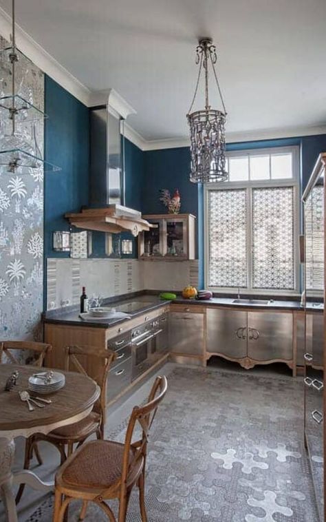 The deep blue wall in this kitchen interior matches well with the elegant kitchen decor. A cylindrical chandelier illuminates this kitchen offering natural wood cabinetry with stainless steel doors and drawers. It includes a hanging glass rack and sleek vent hood. Get more eclectic kitchen decoration ideas in our collection. #kitchen #interior #eclectic (LGD) Courtesy of  Валентина Савескул Eclectic Kitchen Design, Eclectic Kitchen Decor, Elegant Kitchen Decor, Decorative Tile Backsplash, Wood Plank Ceiling, Modular Kitchen Design, Eclectic Kitchen, Wood Beam Ceiling, Wide Plank Flooring