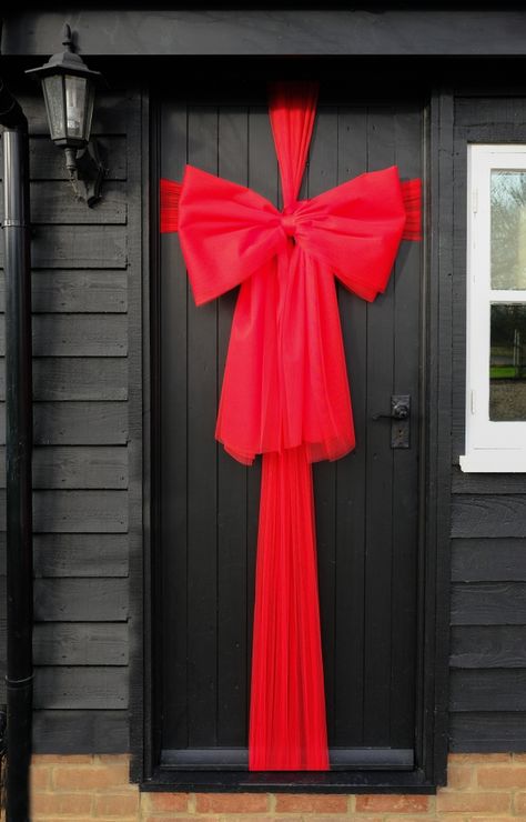 Ribbon On Windows For Christmas, Christmas Front Door Ribbon, Christmas Wrapped Door, Christmas Ribbon On Door, Red Christmas Door Decoration, Door Wrapping Christmas, Christmas Bow Decor Ideas, Christmas Bow For Door, Wrapping Door For Christmas