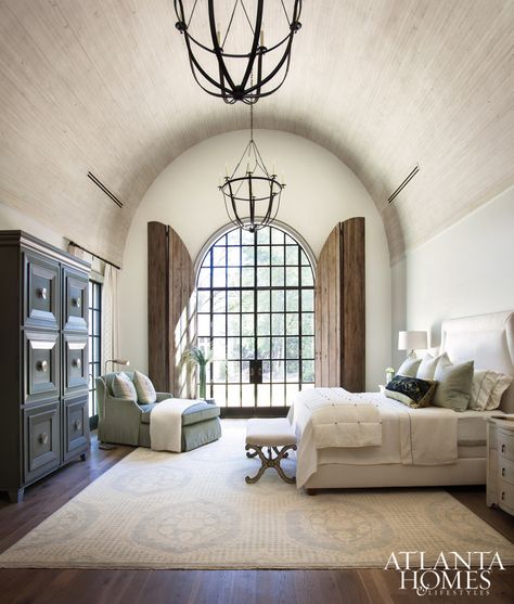 The 18-foot barrel-vault ceiling in the master bedroom is more dimensional thanks to antique-finished wooden boards. Judy Long, a decorator friend of Lisa and Michael, devised the solution for arched door shutters for privacy and to protect from harsh lighting. Shutters Repurposed Decor, Barrel Vault Ceiling, Black Curves, Atlanta Homes, Tuscan Style, Master Bedrooms, White Box, Living Room Paint, Spanish Style