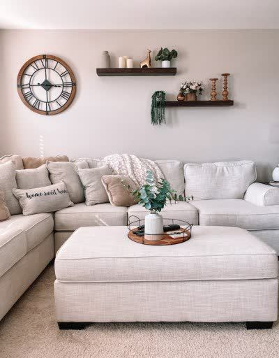 Cream sectional sofa adorned with wood floating shelves and natural decor accents. Neutral living room decor inspiration includes extra large wall clock, wood and metal tray and faux eucalyptus centerpiece. Cream throw pillows, cream leopard throw blanket and more adorn my large cream couch in my coastal decor style lounge space. Source list included. #creamsectional #creamcouch #neutraldecor #coastalstyle #fauxgreenery #fauxeucalyptus #woodmetal #industrialdecor #throwpillows #throwblanket Shelves Over Couch, Loft Living Room Decor, Cream Sofa Living Room, Shelves Above Couch, Coastal Style Decor, Couch Wall Decor, Loft Living Room, Photowall Ideas, Sofa Wall Decor