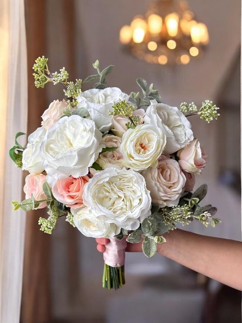 The blush pink bridesmaid bouquet is a stunning arrangement that perfectly complements any wedding theme with its soft, romantic hues. Featuring a delicate blend of blush pink, peach, and cream tones, this artificial bouquet combines the elegance of cream roses with the subtle beauty of peach wedding flowers. The carefully crafted design ensures that the bouquet looks as fresh and vibrant as real flowers, making it a lasting keepsake from your special day. Ideal for both bridesmaids and the brid Light Pink And Cream Wedding, Blush Pink And White Bouquet, Peach And Sage Wedding Flowers, Blush And White Wedding Flowers, Peach And White Wedding Bouquet, Peach Themed Wedding, White And Blush Wedding Flowers, Blush Pink Wedding Theme, Cream Rose Bouquet