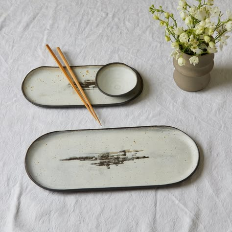 Black and white oval trays A series of oval trays, minimalistic and elegant, with black clay showing through the white porcelain in a playful contrast. Each tray has a unique textured pattern, like an ancient, secret writing which makes it more mysterious, and unrepeatable. The trays are available in three sizes; to use separately or as a set.  Great for serving sushi or cake or to arrange chopped vegetables on. The tiny bowl in the picture can complete the set as a side dish for soy sauce, wasa Sushi Plate Ceramic Handmade, Japanese Plate Set, Sushi Platter Ceramic, Ceramic Compartment Plate, Sushi Serving Set, Sushi Plates Pottery, Pottery Sushi Plate, Sushi Tray Ceramic, Sushi Ceramic Pottery