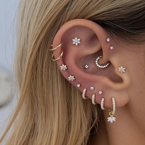 Bloom with Elegance: Flower Ear Curation 🌸Bring the beauty of flowers to your jewelry collection with this ear curation. #flowerearrings #earcuration #bloom #jewelry #fashion #accessories #style Cluster Piercing Ears, Boho Piercings Ears, Mixed Metal Ear Styling, Earring Layering Ideas, A Bunch Of Ear Piercings, Ear Piercings All The Way Up, Three Lobe Piercing Ideas, Lots Of Ear Piercings Silver, Cartlidge Piercing Placement