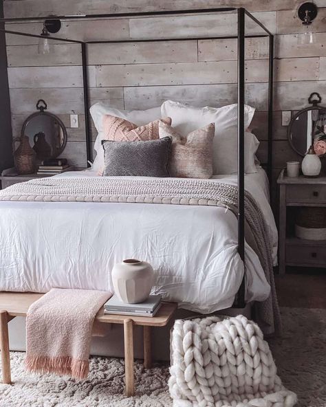 A black metal four poster bed frame is the focal point of this bedroom, along with a rustic wood shiplap wall. A white duvet with a woven blankets and textured throw pillows accessorize the queen bed, with a wood bench set at the foot. Two side tables with metal mirrors sit on either side of the bed frame. Metal Four Poster Bed, Coastal Farmhouse Bedrooms, Poster Bed Frame, Four Poster Bed Frame, Wood Shiplap Wall, Four Post Bed, Wood Shiplap, 4 Poster Beds, Shiplap Wall