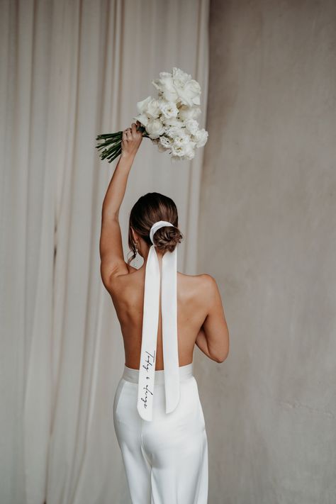 Bride with her back to teh camera wearing only a pair of bridal trousers and holding a bouquet above her head, also wears her hair tied back in a bun and secured with a long silk ribbon that has personalised embroidery on it. Wedding veil design by Rebecca Anne Designs. Bridal Hair Ribbon, Wedding Veil Styles, Bride Veil, Duchess Satin, Hair Ribbon, Bride Accessories, Embroidered Wedding, Wedding Ribbon, Bridal Hair And Makeup