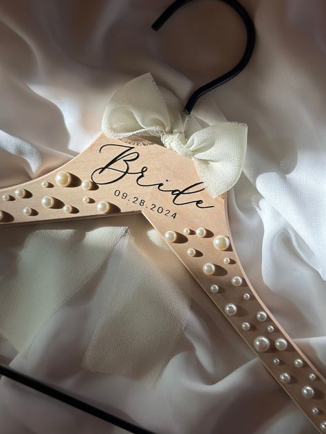 *orders with pearl hangers will included an envelope of extra pearls *  Introducing our personalized pearl wedding hangers, the perfect accessory to add a touch of elegance and sophistication to your big day. These hangers are not just functional but also serve as a beautiful keepsake for years to come. Each hanger can be personalized with the name or initials of the bride, bridesmaid, groom, groomsmen, flower girl, mother of the bride, or mother of the groom, making them a thoughtful and meanin Diy Wedding Hangers Bridesmaid, Wedding Day Hangers, Wedding Day Accessories Brides, Bridesmaid Proposals Unique, Bride Hanger Diy, Pearl Hangers Wedding, Bride To Be Accessories, Mother Of The Bride Ideas, Day Of Wedding Gifts For Bridesmaids