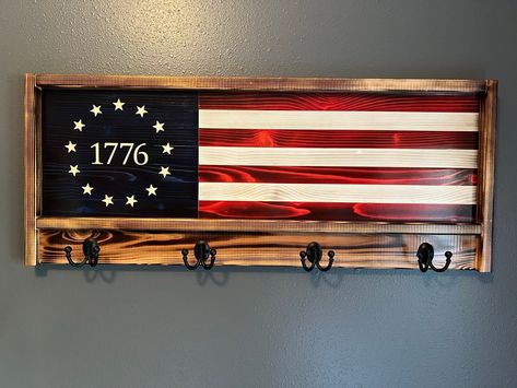 "Look no further If you're looking for that perfect rustic patriotic centerpiece, or great gift idea. This one of a kind pictured handcrafted rustic wood flag measures 39\" Wide  X 16\" tall.  WE CAN CREATE THIS COAT/HAT RACK IN ANY FLAG STYLE YOU WOULD LIKE  Each piece of wood is hand selected and uniquely prepared to ensure a truly wonderful and striking piece. The stripes are stained Red and the union is blue. The seven stripes are glued together with interior/exterior glue. Each star is meticulously engraved. The flag is then charred to perfection. The frame of the flag is made from 5/4\" Cedar, with four hooks attached.Two heavy duty aligator clips supplied for hanging.  Each flag is finished with four coats of indoor/outdoor clear Gloss or Satin Minwax Helmsman spar urethane. Flag Co Flag American Art, Gifts Made With Wood, American Flag Coat Rack, American Flag Decor Diy, Patriotic Wood Projects, Wood Flag Ideas, Wood Craft Show Ideas, Wood Projects That Sell Ideas, American Flag Wood Projects