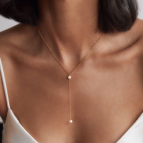 LILY & ROO's delicate gold pearl lariat necklace. Lovingly handmade in our London studio, this stunning lariat necklace is made from 14ct. gold filled chain and a genuine hand-selected freshwater seed pearl. The perfect jewellery for her. All gold pearl lariat necklaces come in a luxury LILY & ROO gift box as standard. Gold Filled means a layer of pure gold pressure-bonded to the core metal. Gold filled items are 5 to 10 times thicker than gold plating. Give your jewellery a little TLC to keep your jewellery shining bright. Your stunning single pearl lariat will be sent to you in a complimentary Lily & Roo gift box with ribbon tied in a beautiful bow. Silver Back Necklace, Elegant Wedding Necklace, Delicate Pearl Necklace, Minimalist Pearl Jewelry, Lariats Jewelry, Pearl Necklace Designs Unique, Pearl Gold Jewellery, Classy Jewelry Silver, Classy Gold Jewelry