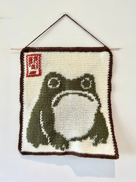 ✨Make your own Matsumoto Hoji frog crochet tapestry!✨ 📏 This tapestry is approximately 34cm x 36cm in size, measured from the bottom of the dowel rod 📏 ✍🏼This pattern includes instructions that have been written out in 3 different ways 1. Stitch Fiddle Graph  2. Colour Block Instructions  3. Written Instructions  🧶Materials needed:🧶 - 4mm crochet hook (can use other sizes at your own discretion) - Brown DK wool - Red DK wool - Dark green DK wool - Cream DK wool - Dowel rod - Scissors - Darn Matsumoto Hoji Frog, Plant Crochet Blanket, Crochet Hanging Shelf, Dog Tapestry Crochet, Frog Tapestry Crochet, Pokemon Tapestry Crochet, Crochet Pattern Tapestry, Halloween Crochet Tapestry, Small Crochet Tapestry Pattern